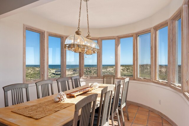 dining area with a water view, light tile patterned floors, and a notable chandelier