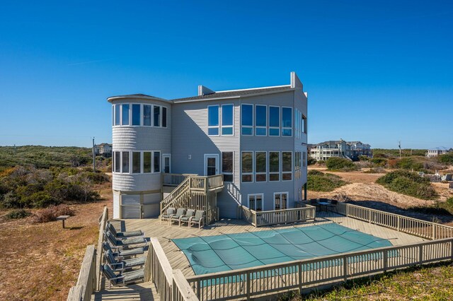 back of house with stairs, a deck, a chimney, and a fenced in pool