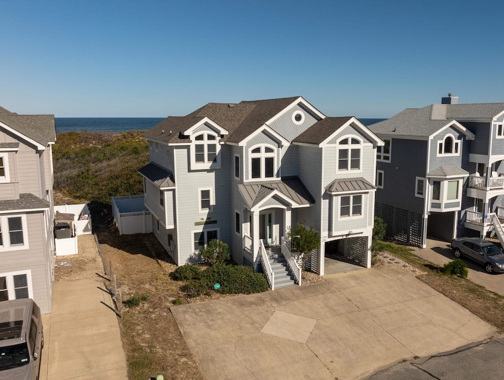 view of front facade with concrete driveway, a residential view, metal roof, a standing seam roof, and a carport