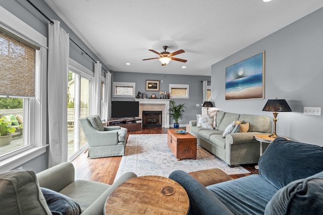 living area featuring a fireplace with flush hearth, light wood-type flooring, a ceiling fan, and recessed lighting