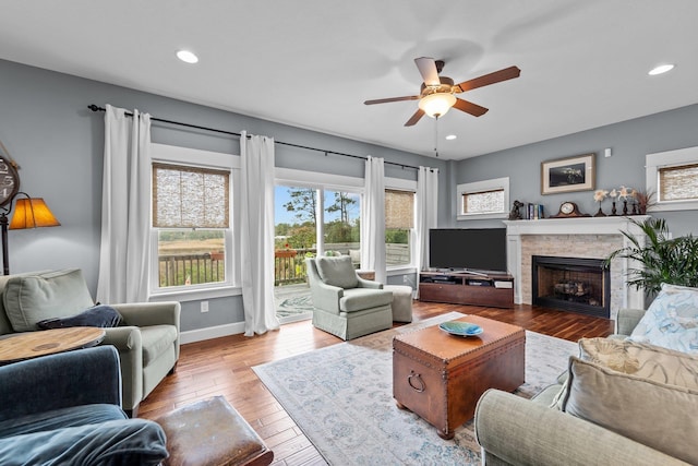 living area featuring light wood-style flooring, a fireplace, baseboards, and recessed lighting