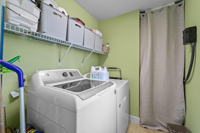 washroom featuring laundry area, light wood-type flooring, independent washer and dryer, and baseboards