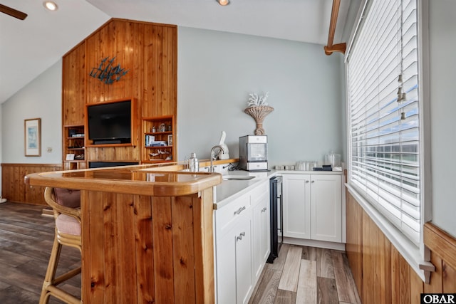 kitchen featuring open floor plan, wainscoting, white cabinets, vaulted ceiling, and wood finished floors