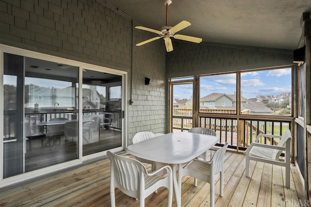 sunroom with lofted ceiling, a residential view, and a ceiling fan