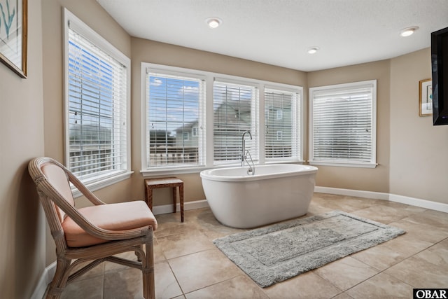 full bathroom featuring a freestanding tub, baseboards, and tile patterned floors