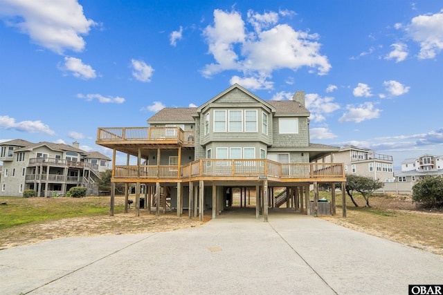 view of front of house featuring a carport, a chimney, concrete driveway, and a wooden deck