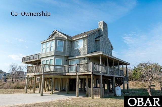 back of property with a carport, driveway, a chimney, and a wooden deck