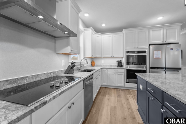 1207 Tail Wind Ct Lot 267, Corolla, NC 27927 - kitchen featuring appliances with stainless steel finishes, wall chimney exhaust hood, a sink, white cabinetry, and light wood-style floors