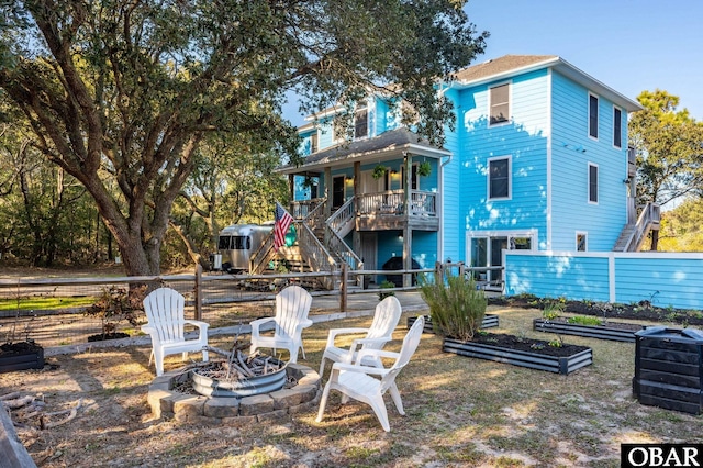 rear view of house featuring a garden, stairway, an outdoor fire pit, and fence