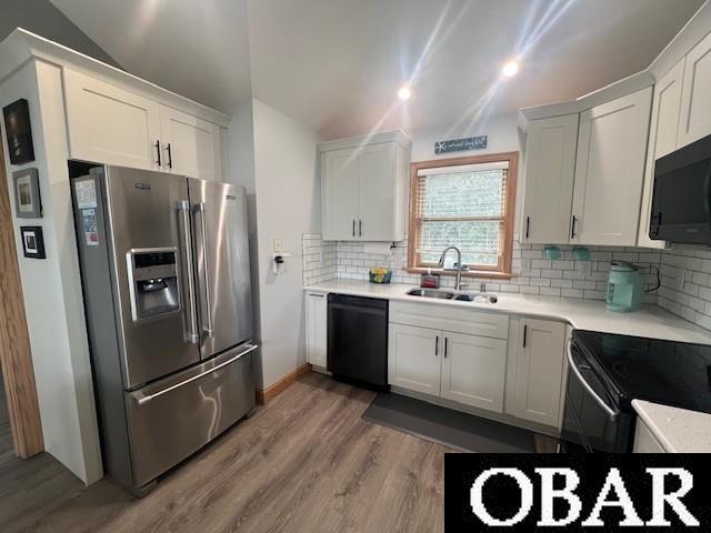 kitchen featuring a sink, black appliances, light countertops, and vaulted ceiling