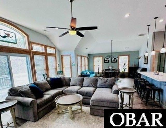 living area featuring lofted ceiling and ceiling fan with notable chandelier