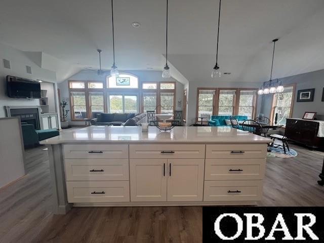 kitchen with a wealth of natural light, open floor plan, white cabinets, and vaulted ceiling