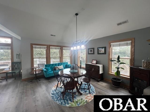 dining room featuring visible vents, light wood-style flooring, baseboards, and vaulted ceiling