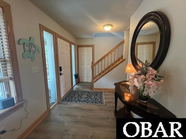 entrance foyer with baseboards, wood finished floors, and stairs