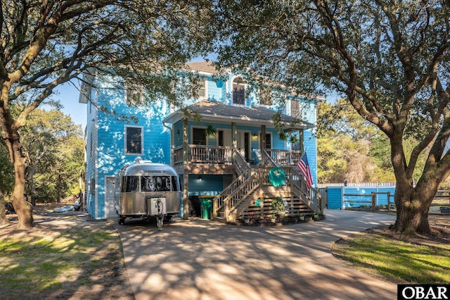 view of front facade with stairway, a porch, and concrete driveway