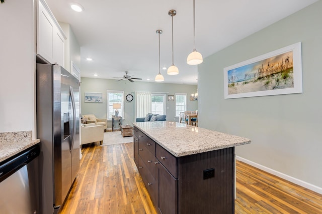 kitchen with light wood-style flooring, ceiling fan with notable chandelier, white cabinetry, stainless steel appliances, and dark brown cabinetry