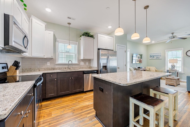 kitchen with visible vents, a sink, open floor plan, stainless steel appliances, and ceiling fan