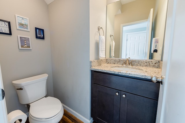 half bath with vanity, toilet, and baseboards