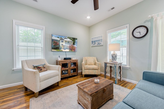 living area featuring ceiling fan, visible vents, baseboards, and wood finished floors