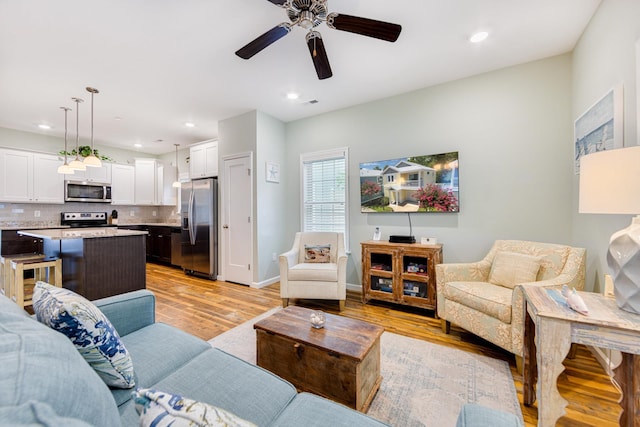 living area featuring recessed lighting, baseboards, light wood-type flooring, and a ceiling fan