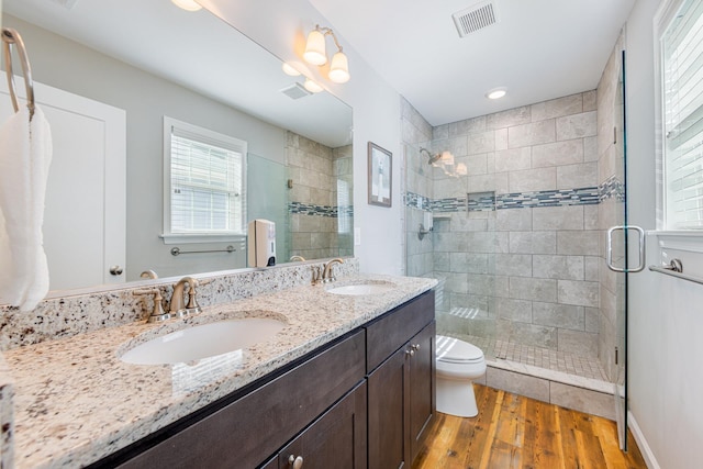 bathroom featuring a sink, visible vents, wood finished floors, and a shower stall