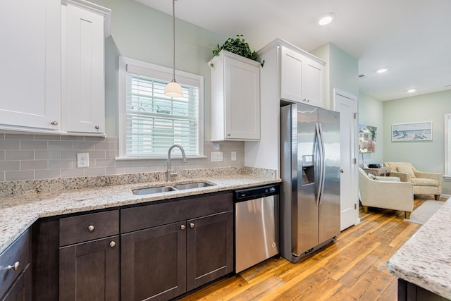 kitchen with a sink, backsplash, white cabinetry, stainless steel appliances, and dark brown cabinets