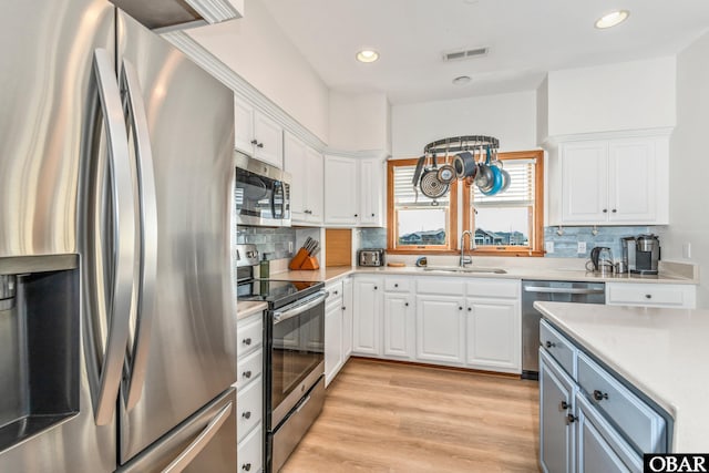 kitchen featuring stainless steel appliances, light countertops, white cabinets, and a sink