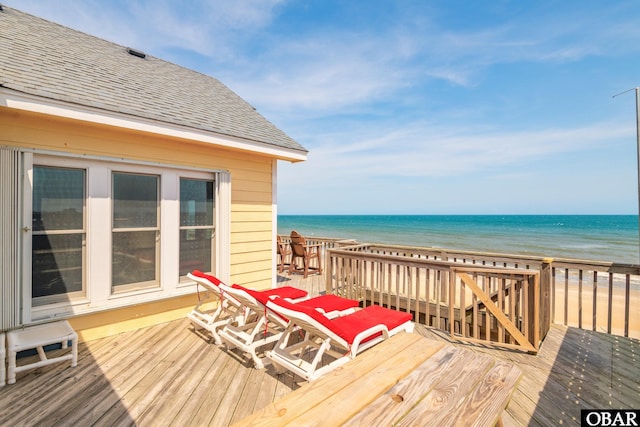 wooden deck featuring a water view and a view of the beach