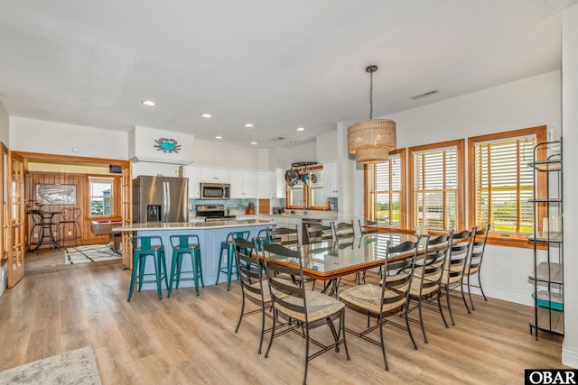 dining space with light wood-style flooring, visible vents, and a healthy amount of sunlight