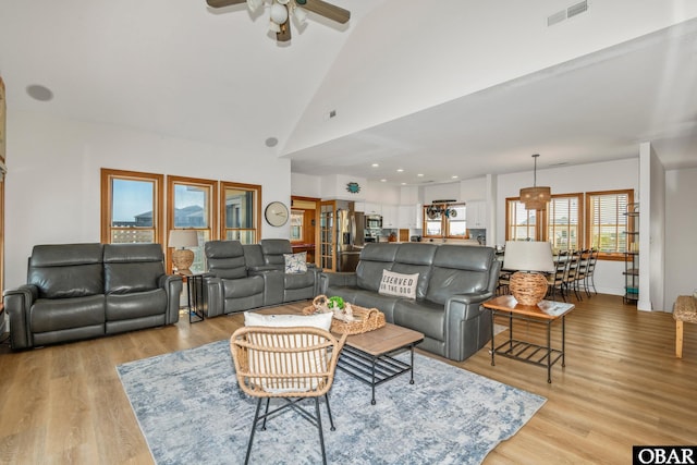 living room featuring light wood finished floors, ceiling fan, high vaulted ceiling, and visible vents