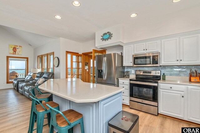 kitchen featuring a kitchen breakfast bar, stainless steel appliances, light countertops, and light wood finished floors