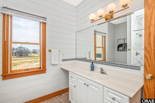 bathroom featuring baseboards, wooden walls, stone finish floor, and vanity