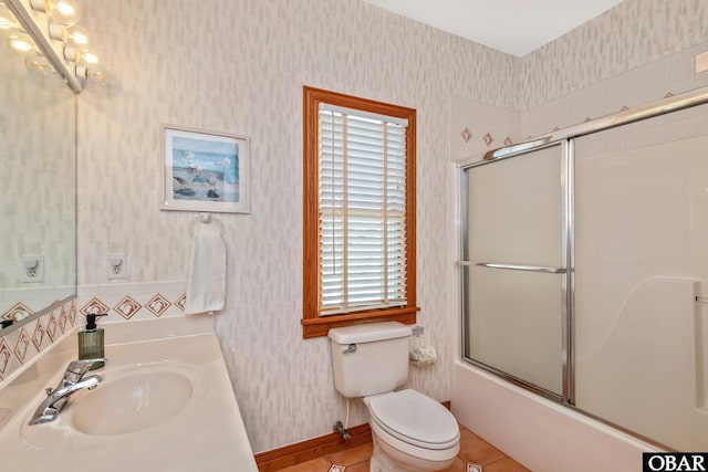 full bath featuring tile patterned floors, wallpapered walls, toilet, and combined bath / shower with glass door
