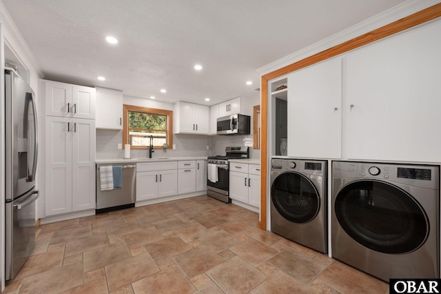 laundry room featuring recessed lighting, washing machine and dryer, stone finish flooring, a sink, and laundry area