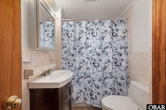 bathroom featuring toilet, curtained shower, a textured ceiling, vanity, and tile walls