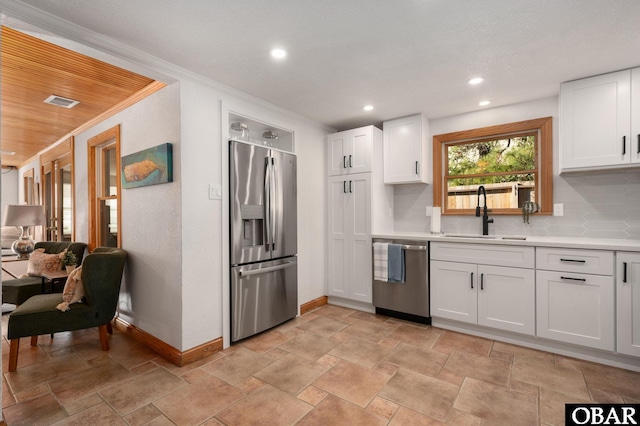 kitchen with stainless steel appliances, light countertops, decorative backsplash, white cabinetry, and a sink