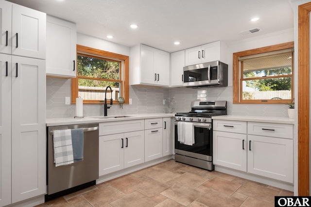 kitchen with a sink, white cabinetry, stainless steel appliances, and light countertops