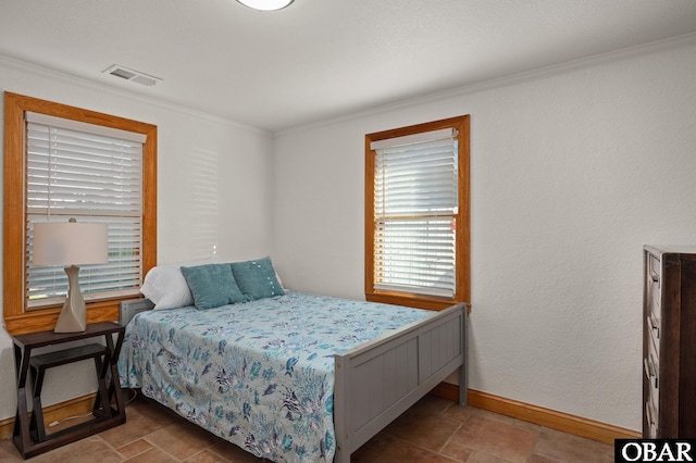 bedroom featuring stone finish flooring, ornamental molding, visible vents, and baseboards