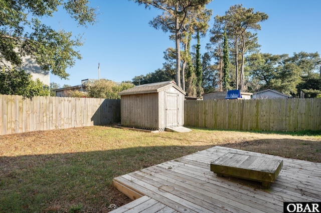 view of yard with an outbuilding, a shed, a fenced backyard, and a deck