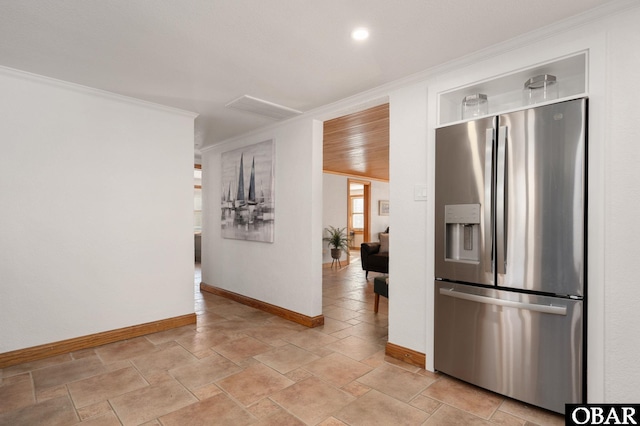 kitchen with ornamental molding, stone finish floor, stainless steel fridge, and baseboards