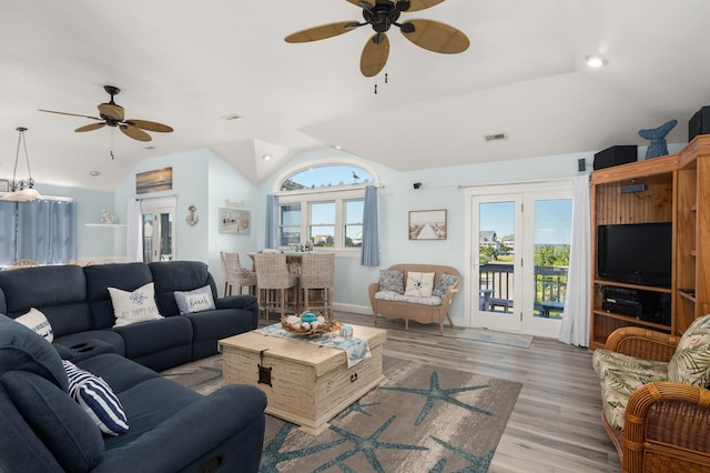 living room featuring lofted ceiling, light wood-type flooring, a ceiling fan, and a wealth of natural light