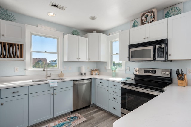 kitchen with light countertops, visible vents, appliances with stainless steel finishes, white cabinets, and a sink