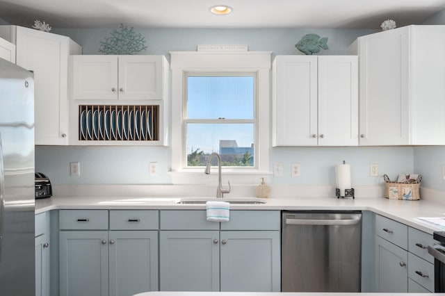 kitchen featuring a sink, white cabinetry, light countertops, appliances with stainless steel finishes, and gray cabinets