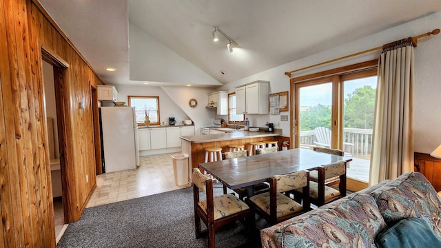 dining space featuring vaulted ceiling, rail lighting, and light colored carpet