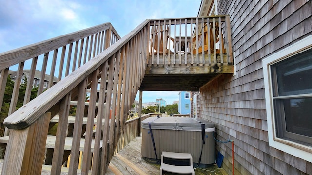 wooden deck with a hot tub and stairs