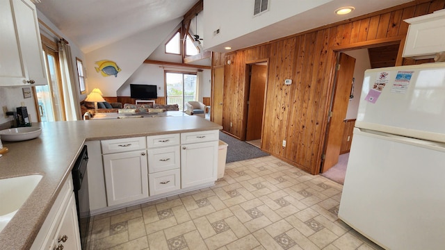 kitchen with white cabinets, decorative light fixtures, freestanding refrigerator, light countertops, and wood walls