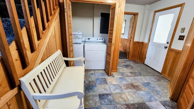 laundry room with a wainscoted wall, laundry area, washer / clothes dryer, and stone finish floor