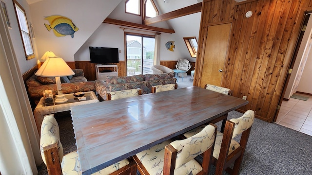 tiled dining space with lofted ceiling, wood walls, carpet, and a wainscoted wall