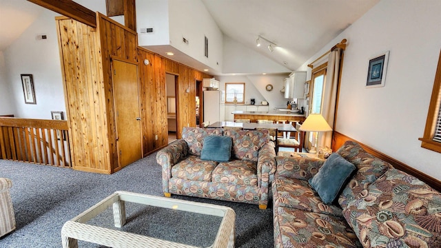 carpeted living area with high vaulted ceiling, rail lighting, visible vents, and baseboards