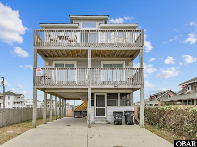 view of front of house featuring driveway, a carport, fence, a balcony, and entry steps